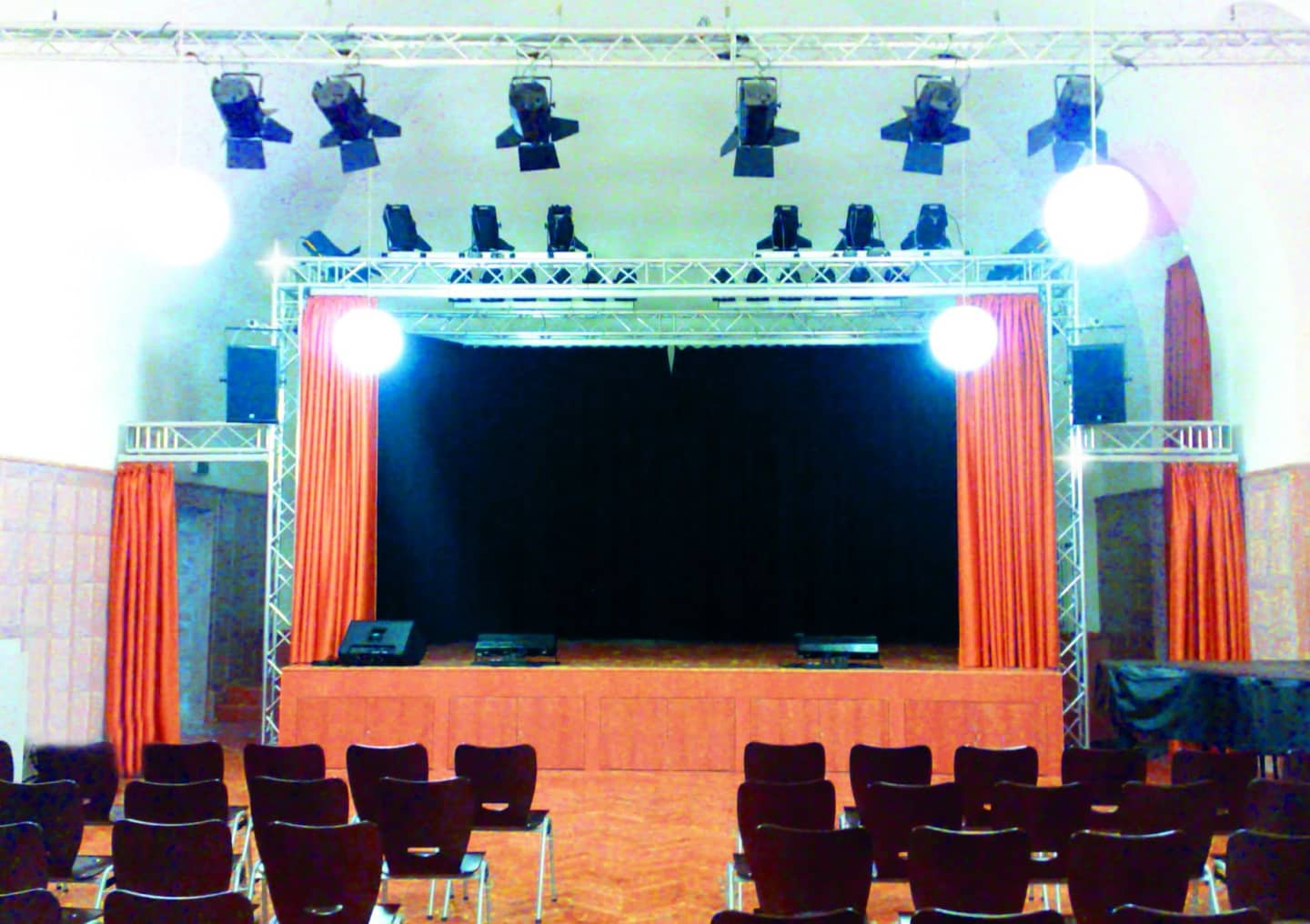 Stage cabinet with spotlights on a truss and main curtain in a hall with seating