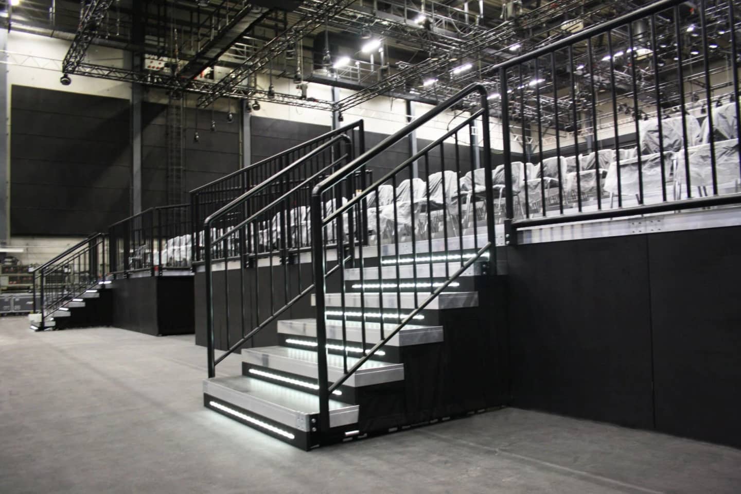 Tribüne mit Aluminiumtreppe, schwarzen Handläufen und Stufenbeleuchtung