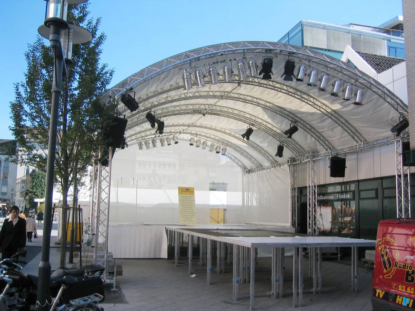 BÜTEC Rundbogendach aus Aluminium-Traversen mit Scheinwerfern über einer Podestbühne